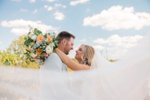 A romantic wedding couple shares intimate moments in a bright outdoor setting with blue skies . Chillicothe Ohio Bell Manor.