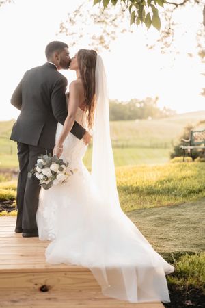 Sunset wedding portraits on a hilltop with flowing white dress and bouquet.