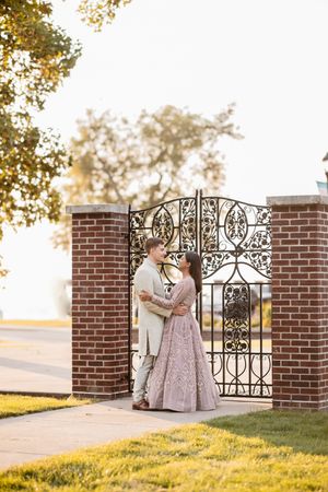 Romantic engagement session by ornate iron gates during golden hour.