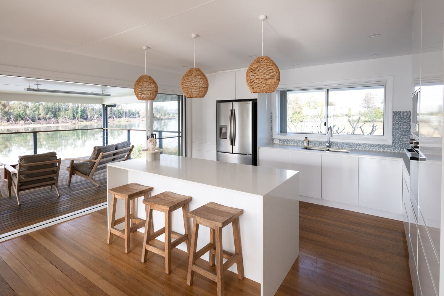 A modern dining room with white walls features natural wood tables and woven rattan pendant lights hanging above.
