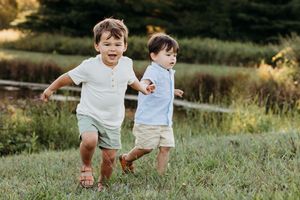 Kids play and explore together in a grassy meadow on a warm summer evening.