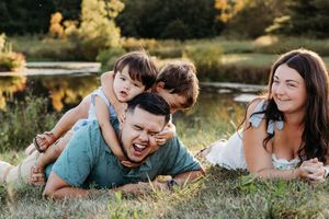 Couple laying in grass during golden hour sunset enjoying playful and intimate moments together at a park.