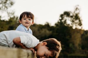 Brother and sister playing together outdoors in natural sunlight during golden hour.