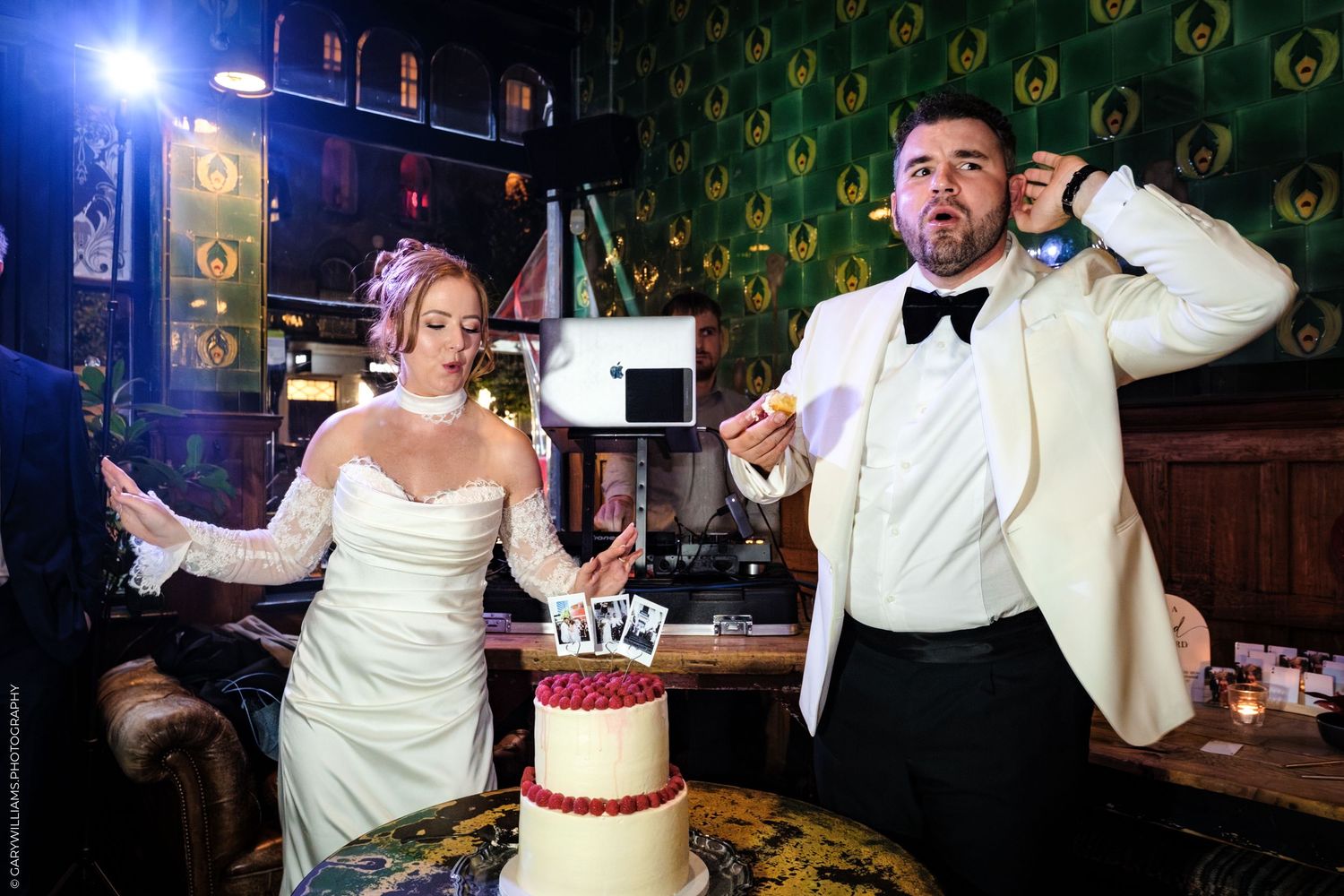 A performer in a white tuxedo jacket and bow tie dances and sings at a vintage-themed nightclub.