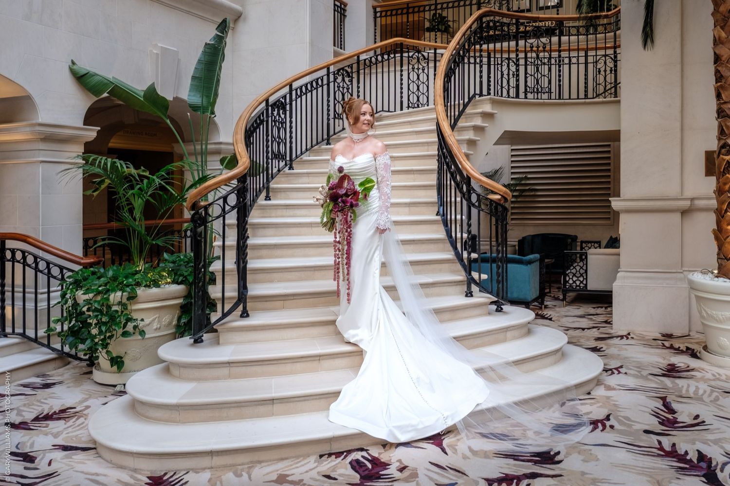 Elegant curved marble staircase with ornate metal railings and decorative elements in a luxury interior setting.