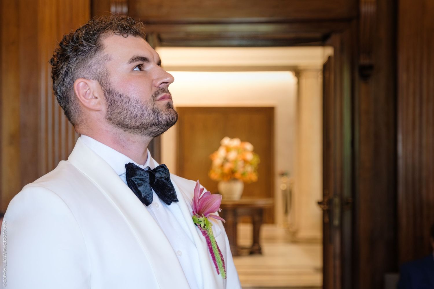 A pair of individuals in formal attire looks to the side during what appears to be a wedding ceremony or elegant event.