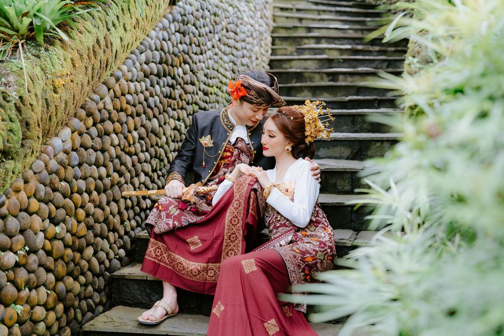 Romantic photoshoot on ornate stone steps with lush tropical garden surroundings.