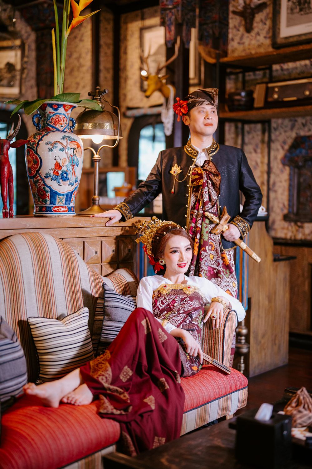Vintage-styled interior scene with burgundy dress on striped antique couch.