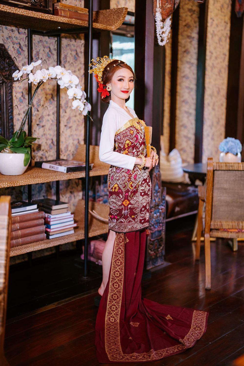 Traditional Javanese wedding photoshoot in an ornate indoor setting with burgundy and gold traditional attire.