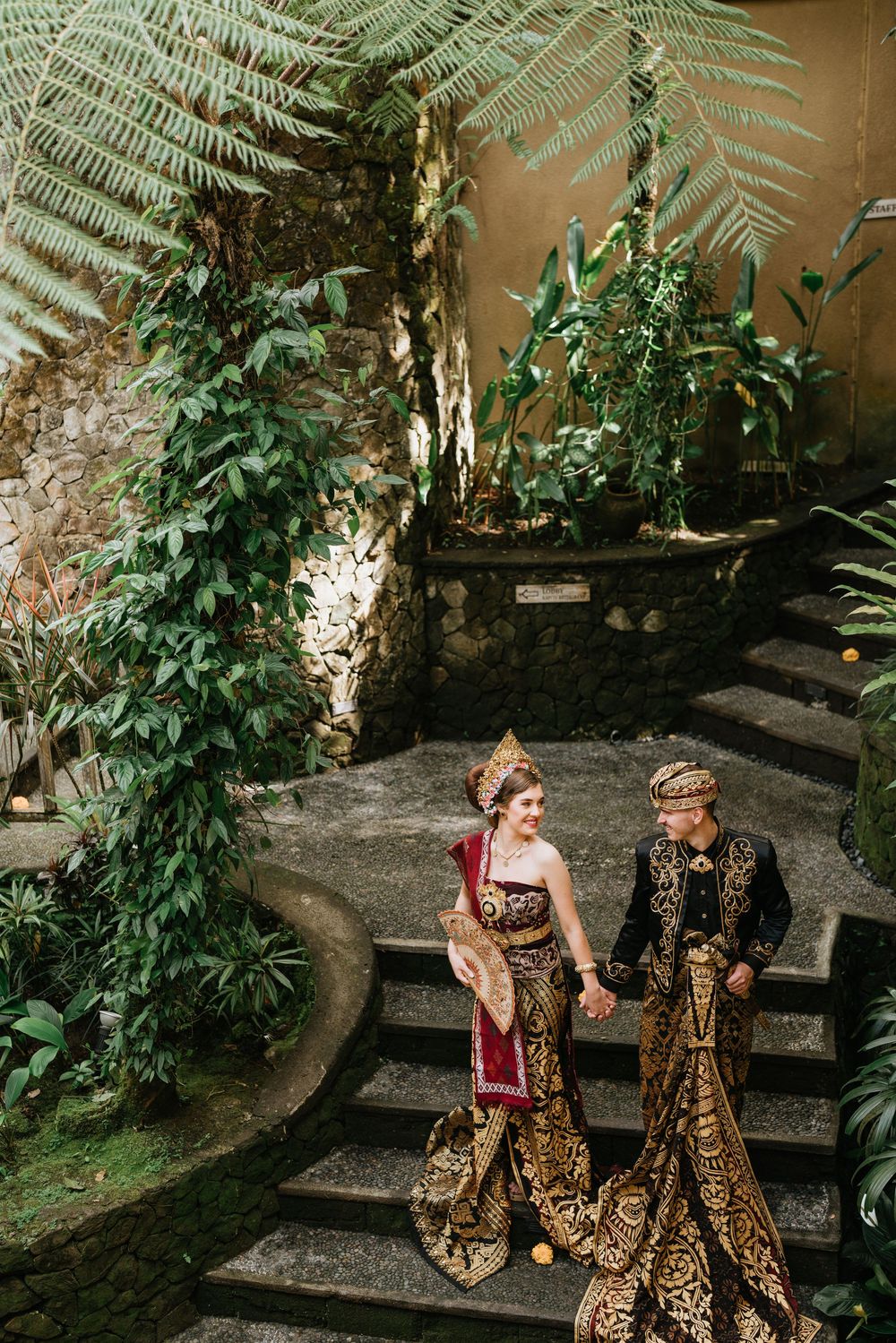 Wedding photoshoot in a garden setting with traditional Indonesian ceremonial dress.