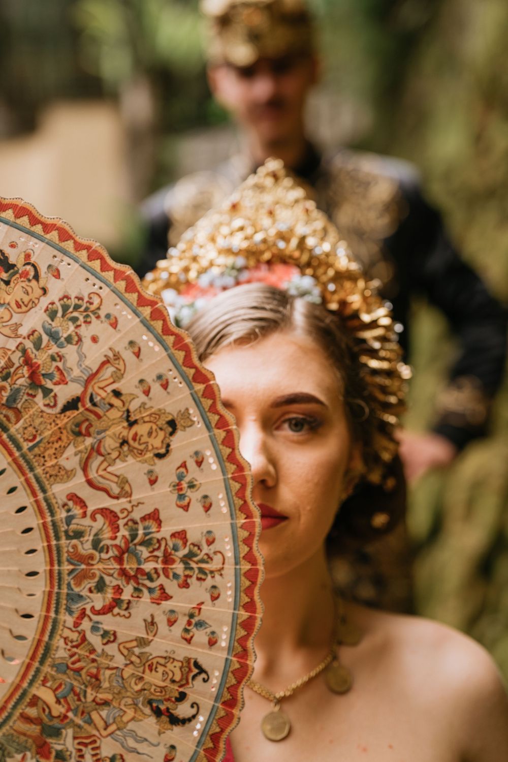 Decorative fan with intricate patterns and gold details against natural background.