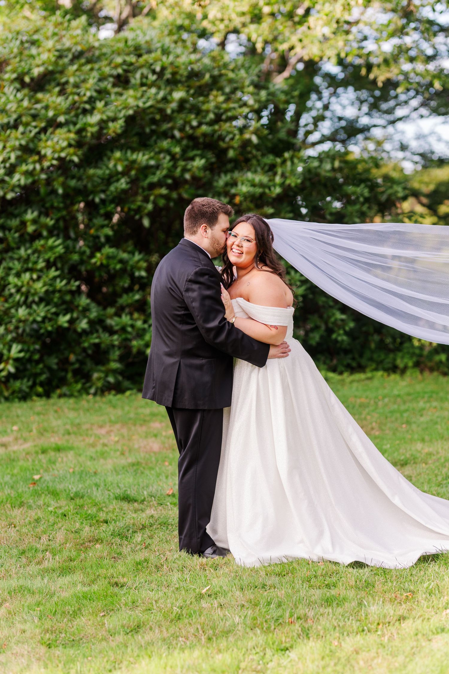 A romantic wedding first look moment captured outdoors with the bride's veil flowing in the breeze.