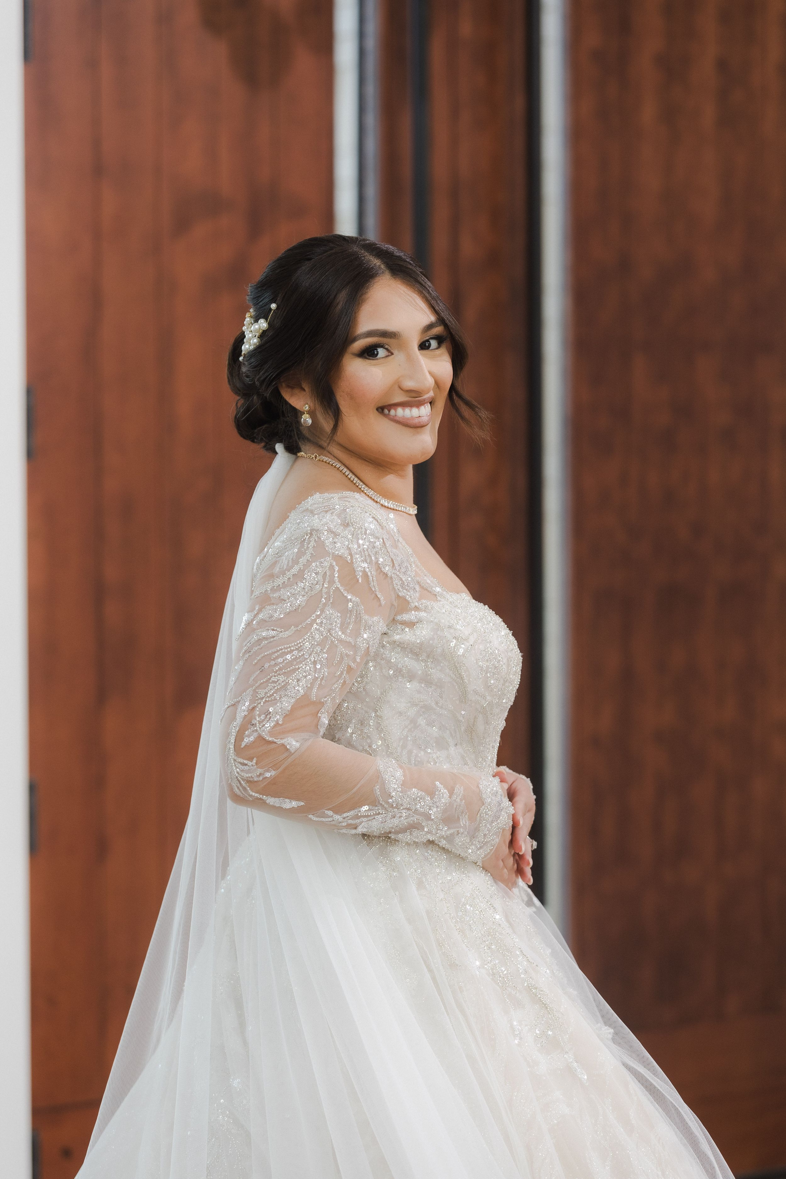 Beautiful wedding dress with intricate lace sleeves and flowing train captured in natural light.