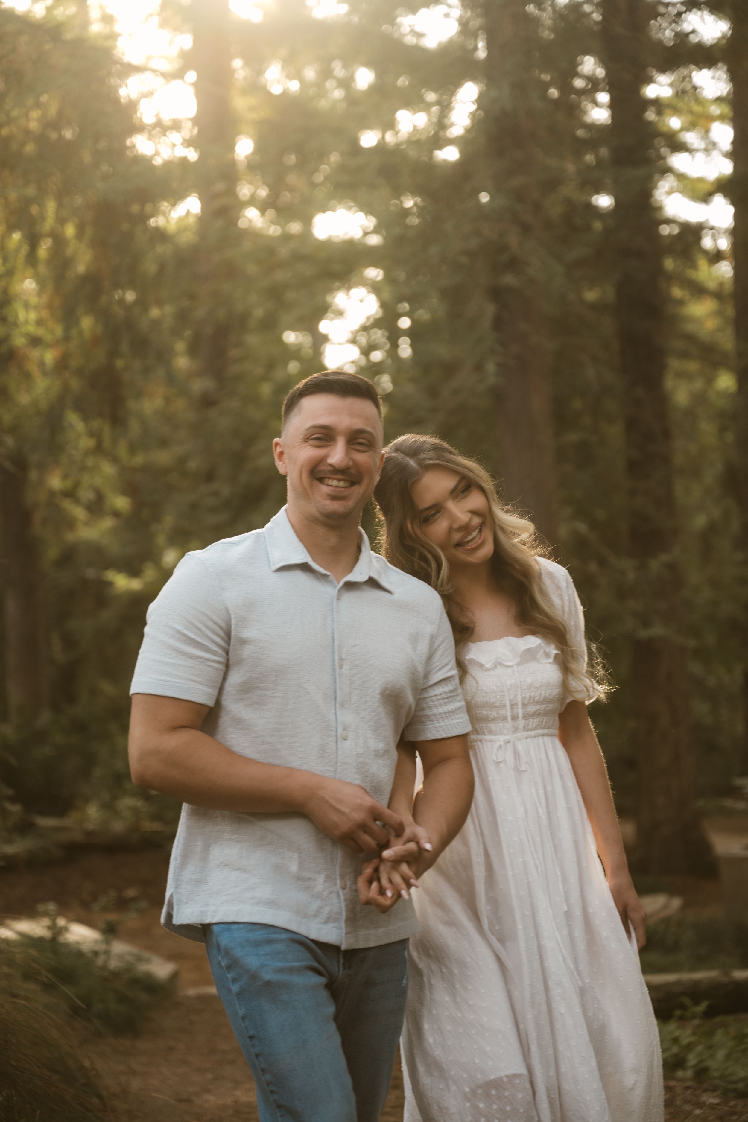 A couple shares laughter during their sunset photoshoot in a wooded setting.