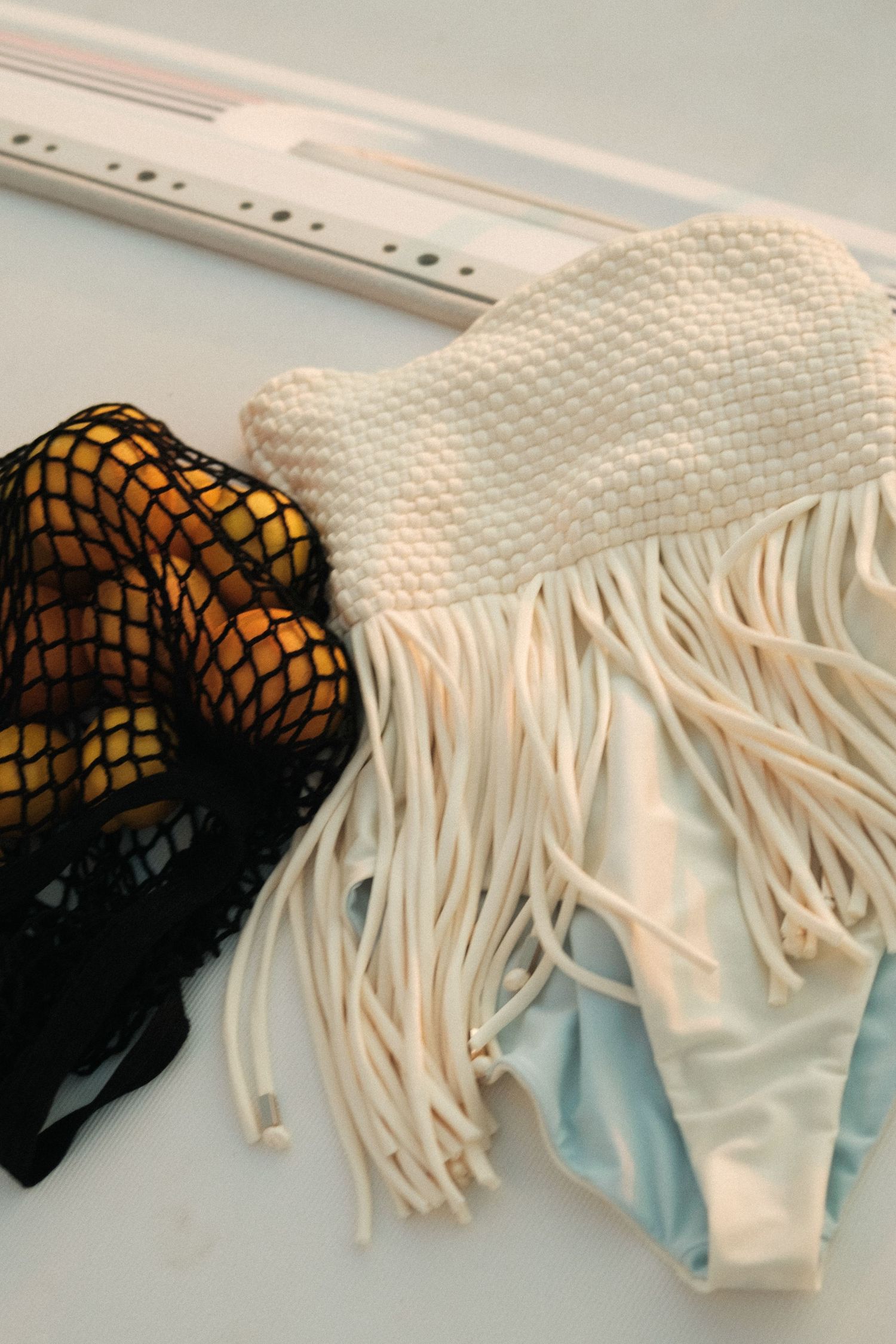 A collection of white and black swimwear with fringe detail displayed against a light background.