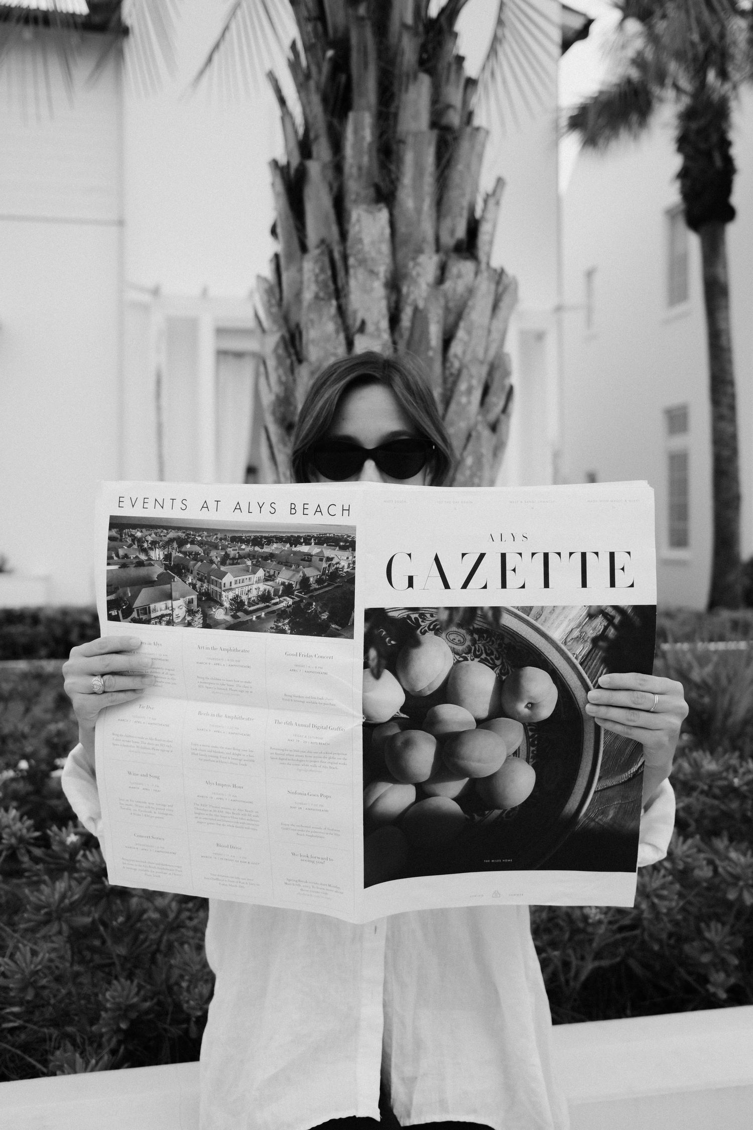 Someone holding up a magazine called Gazette in black and white photography.