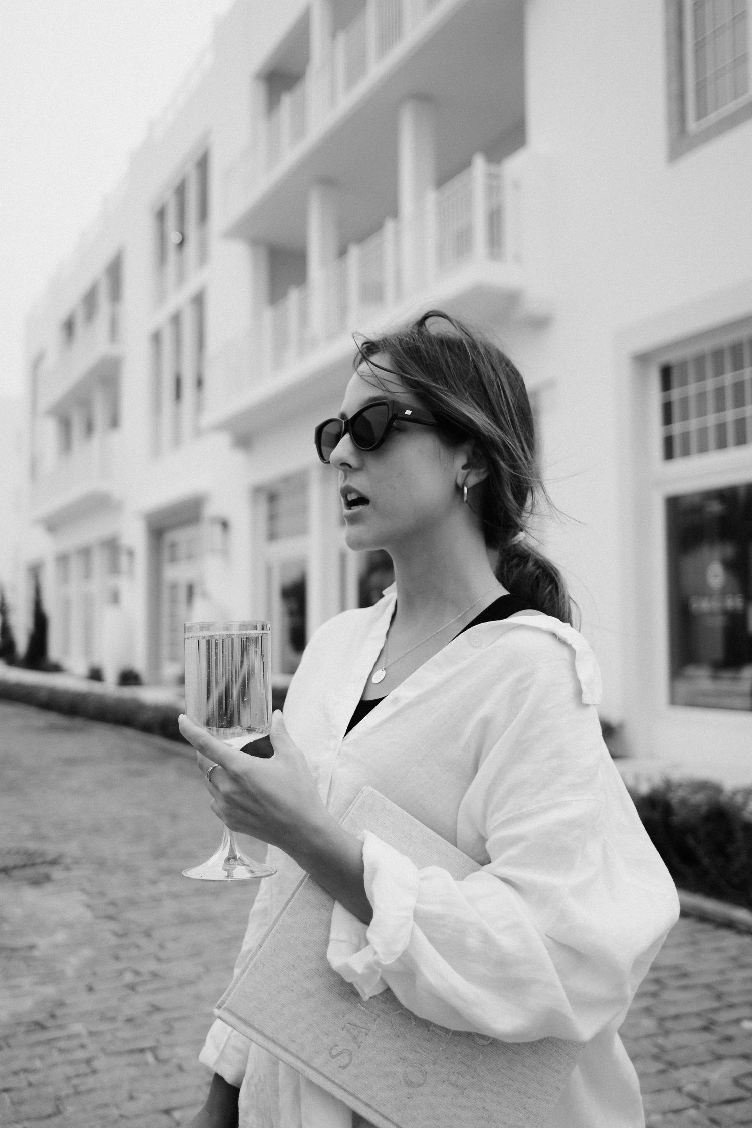 Person in white robe relaxing outdoors against a white building.