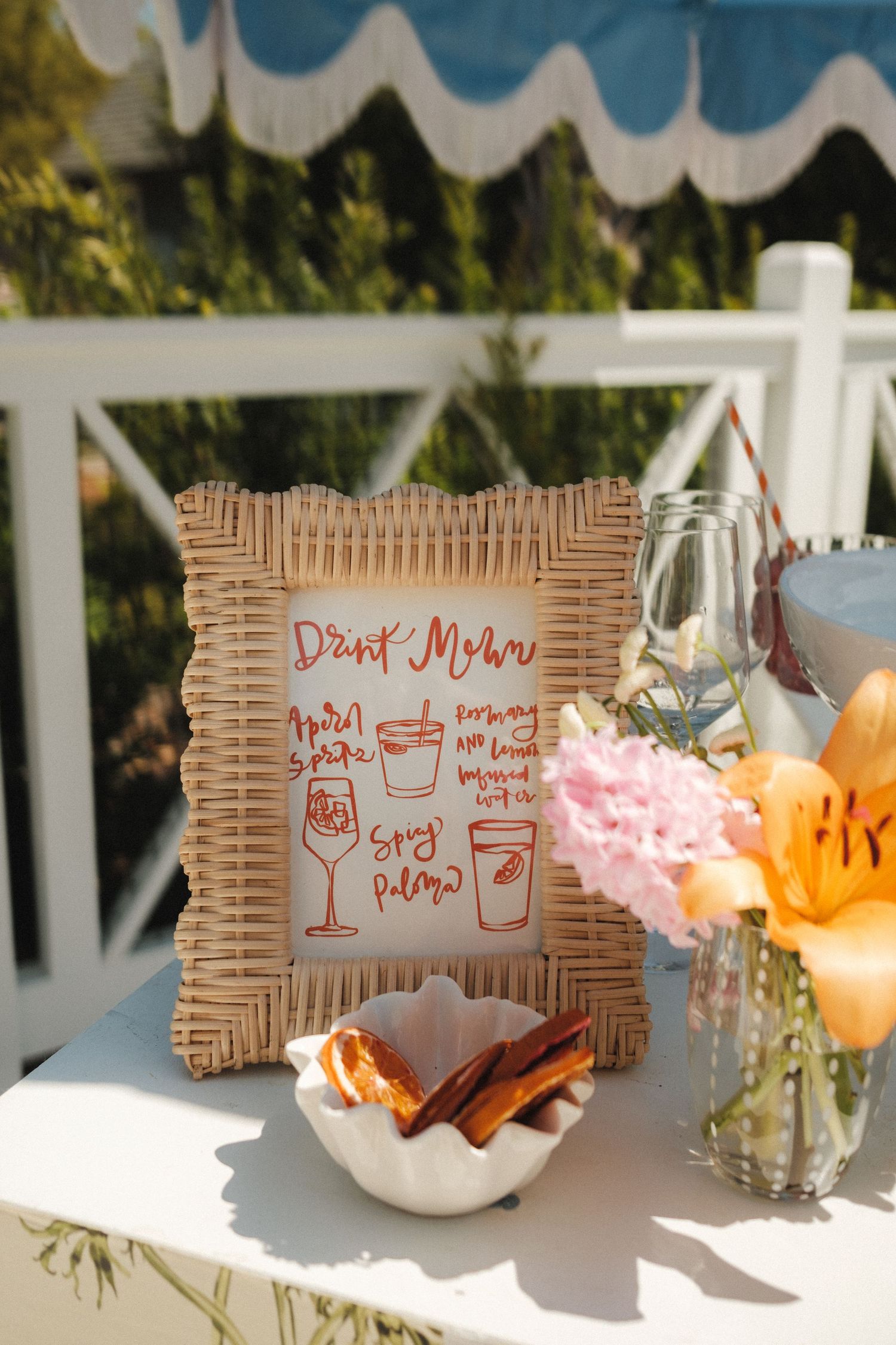 Handwritten menu cards and floral centerpieces on white outdoor table.