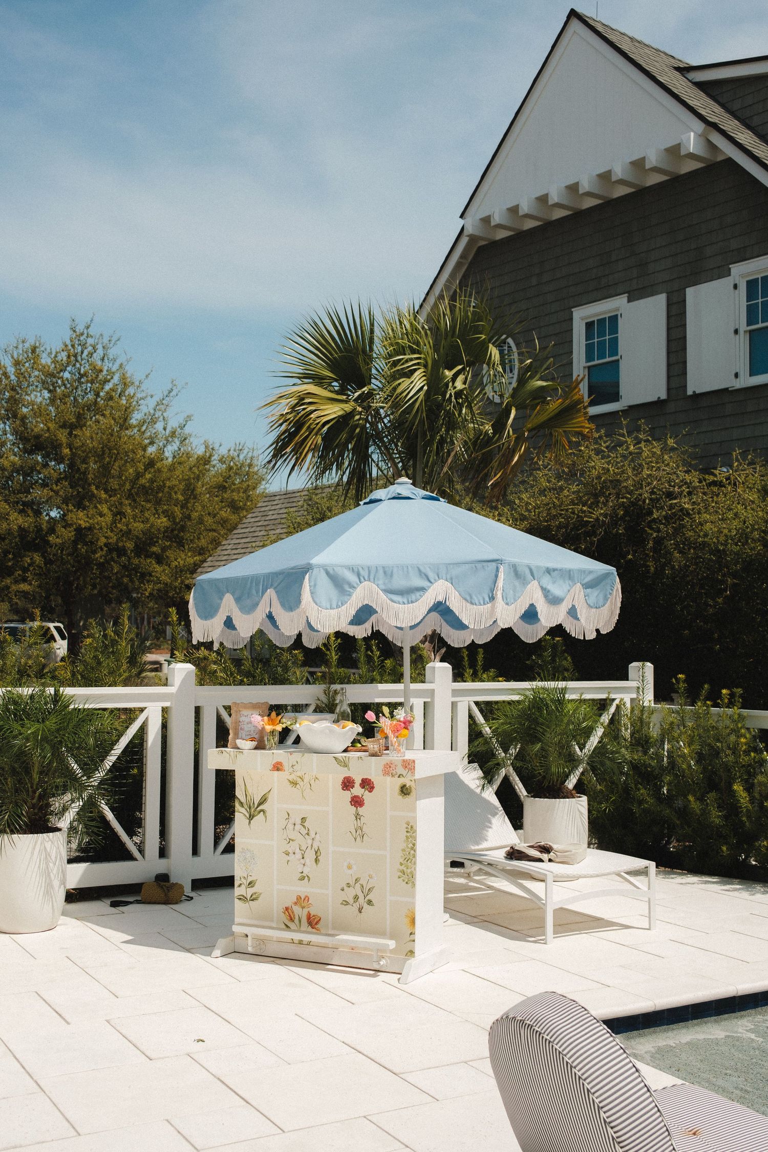 White outdoor patio with scalloped awning and coastal-style furniture.