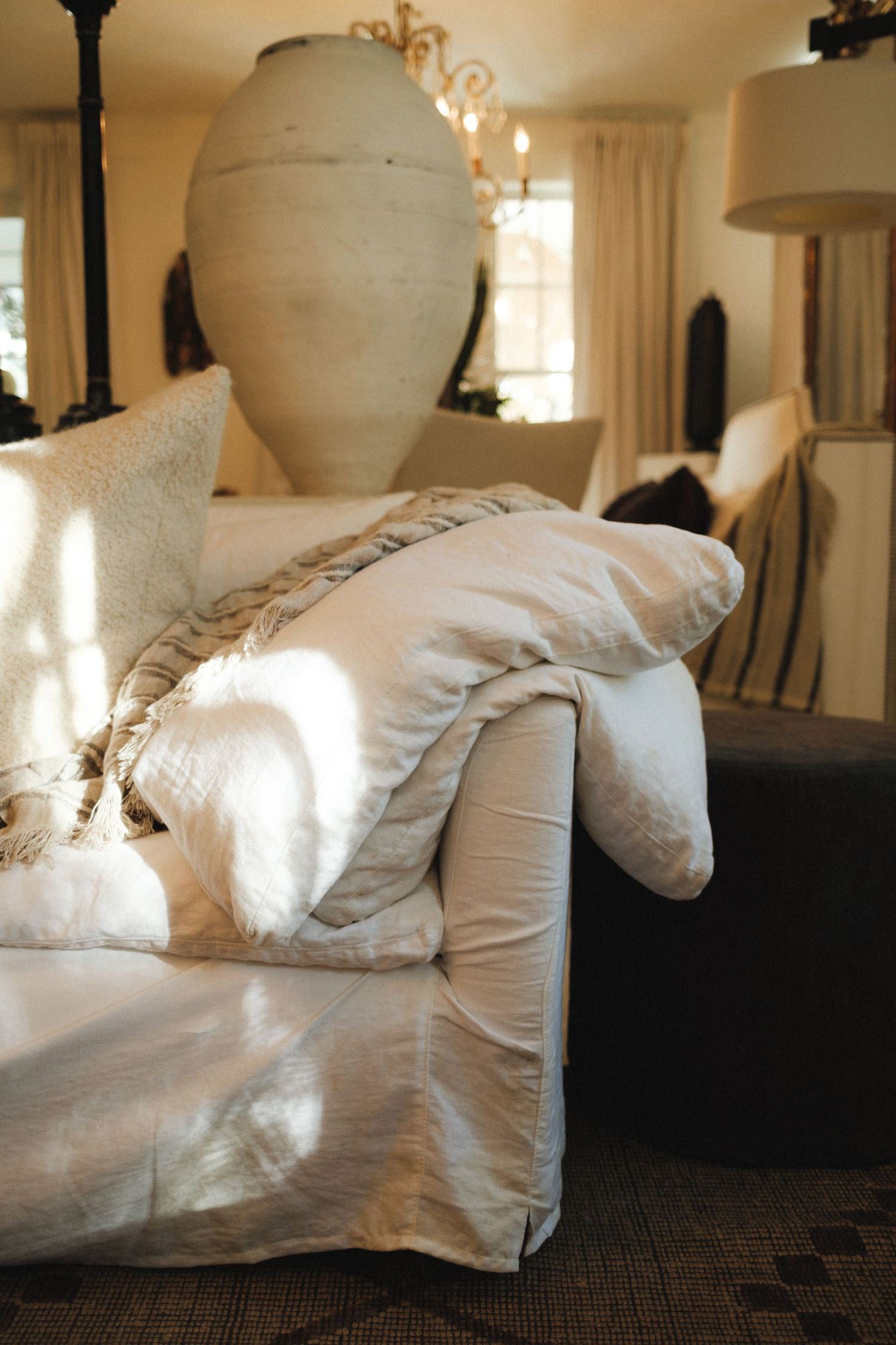 White upholstered sofa with plush cushions in a sunlit room with pendant lighting.