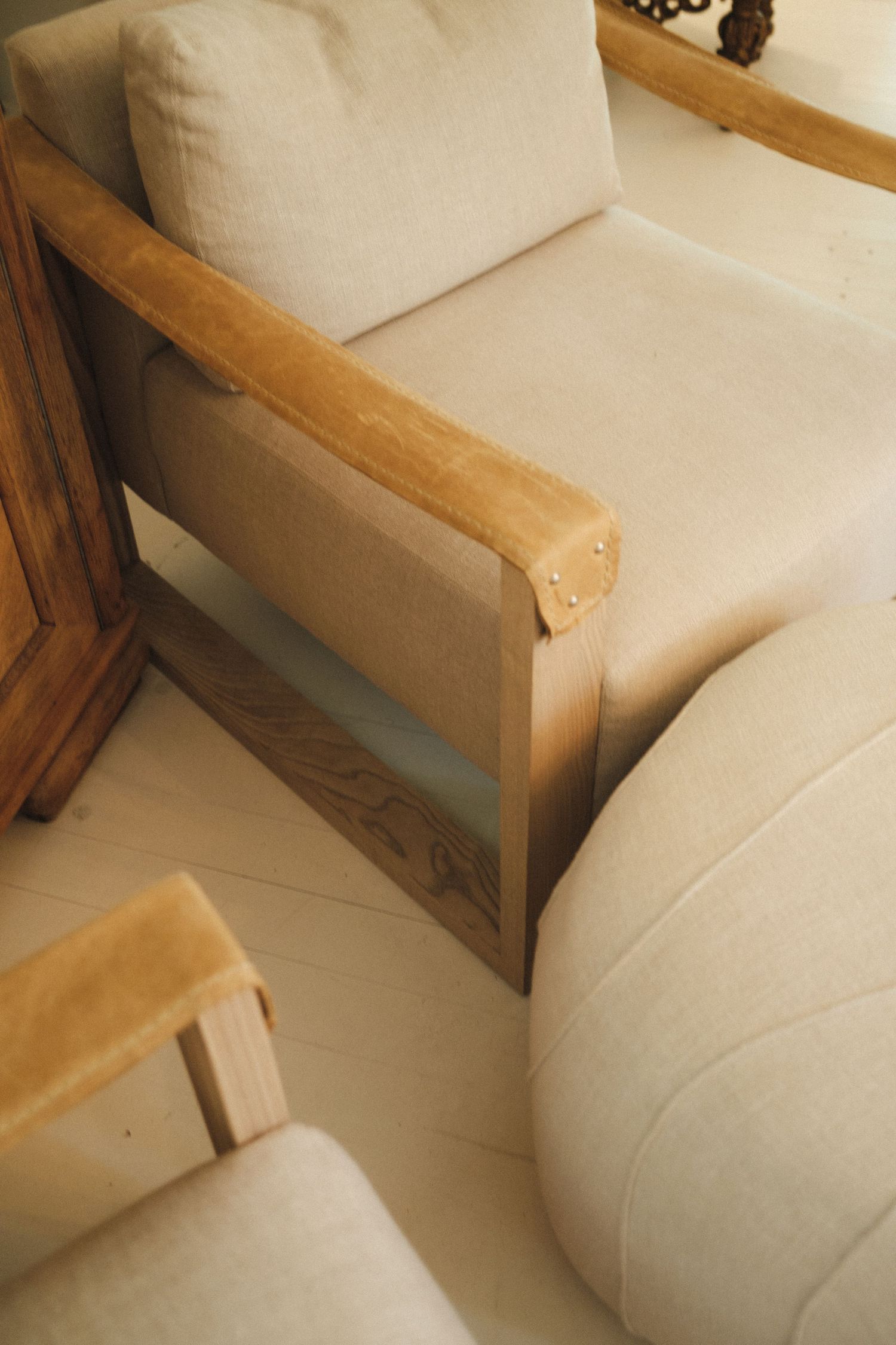 Close-up details of a cream-colored sofa with wooden frame arms in a modern living space.