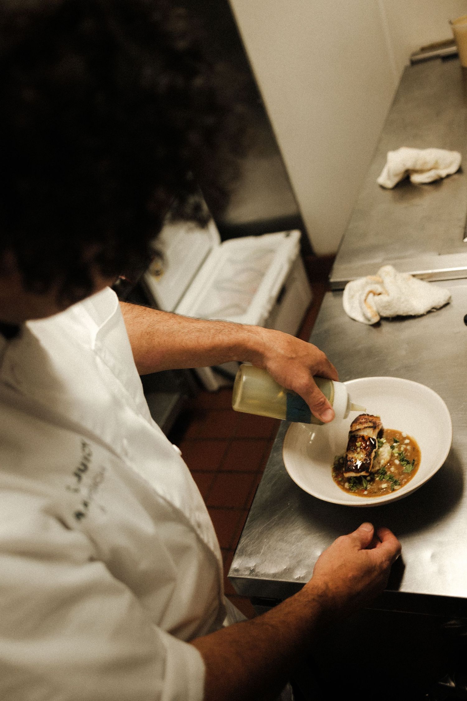 Chef's hands plating gourmet dishes in a professional kitchen.