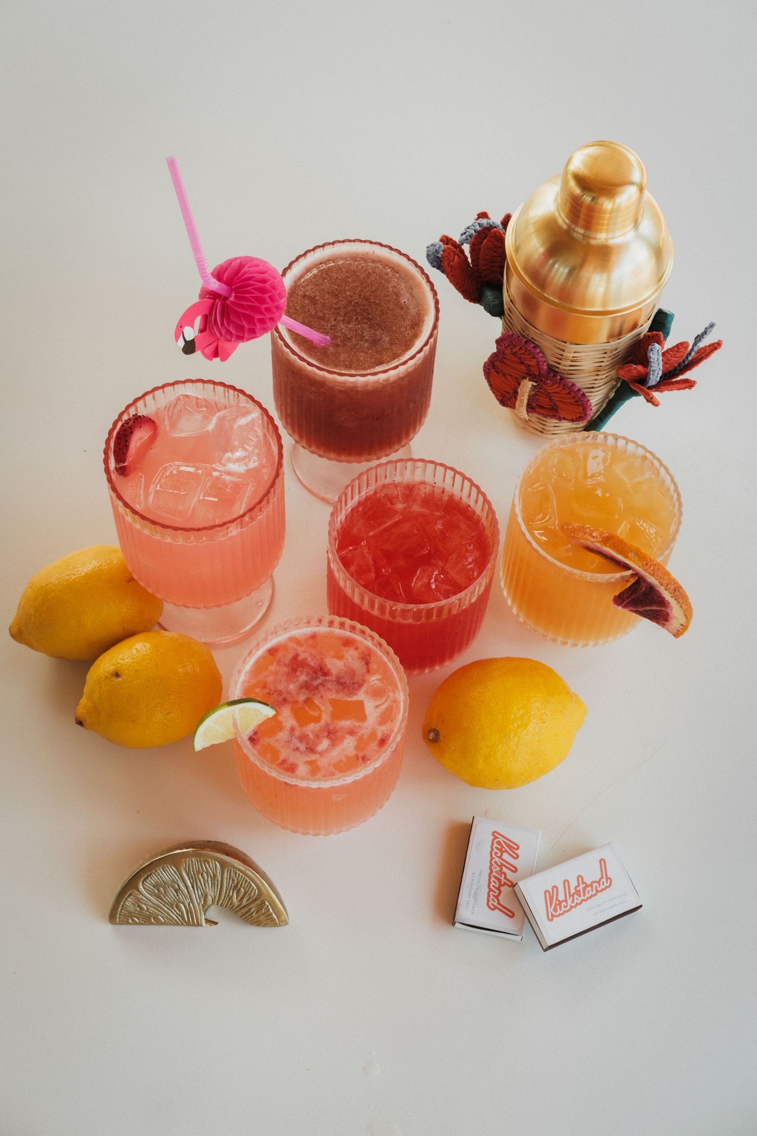 Colorful summer cocktails with citrus garnishes arranged on a white surface.