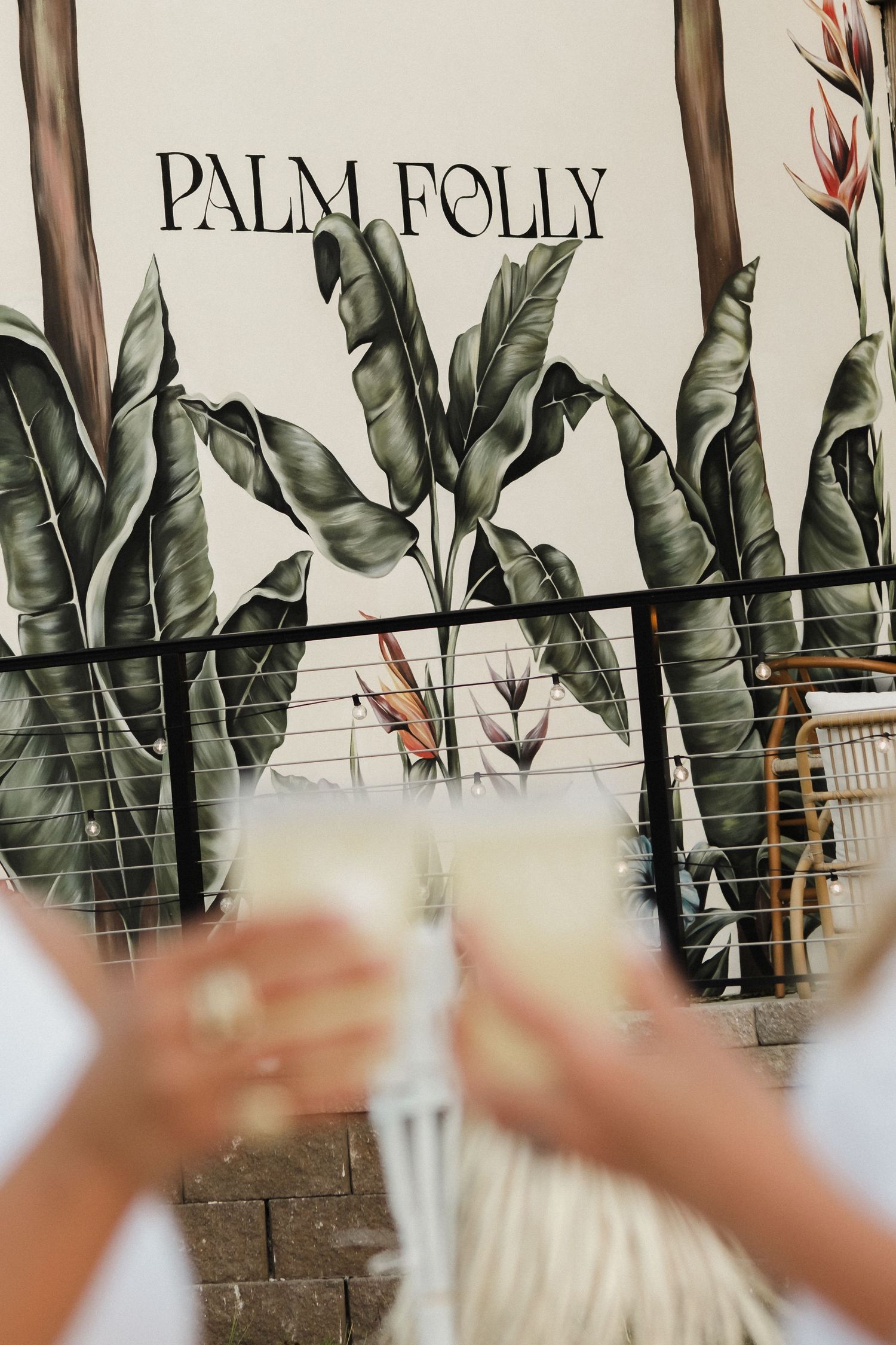 Tropical palm leaf mural wall design with Palm Folly branding.