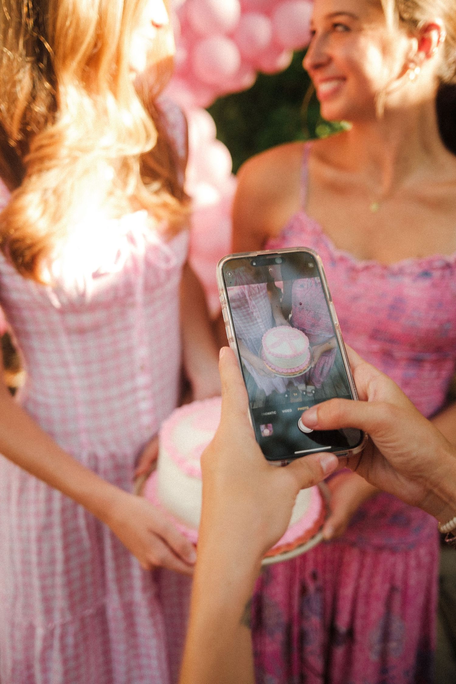 Pink gingham dresses and mobile phones at an outdoor party.
