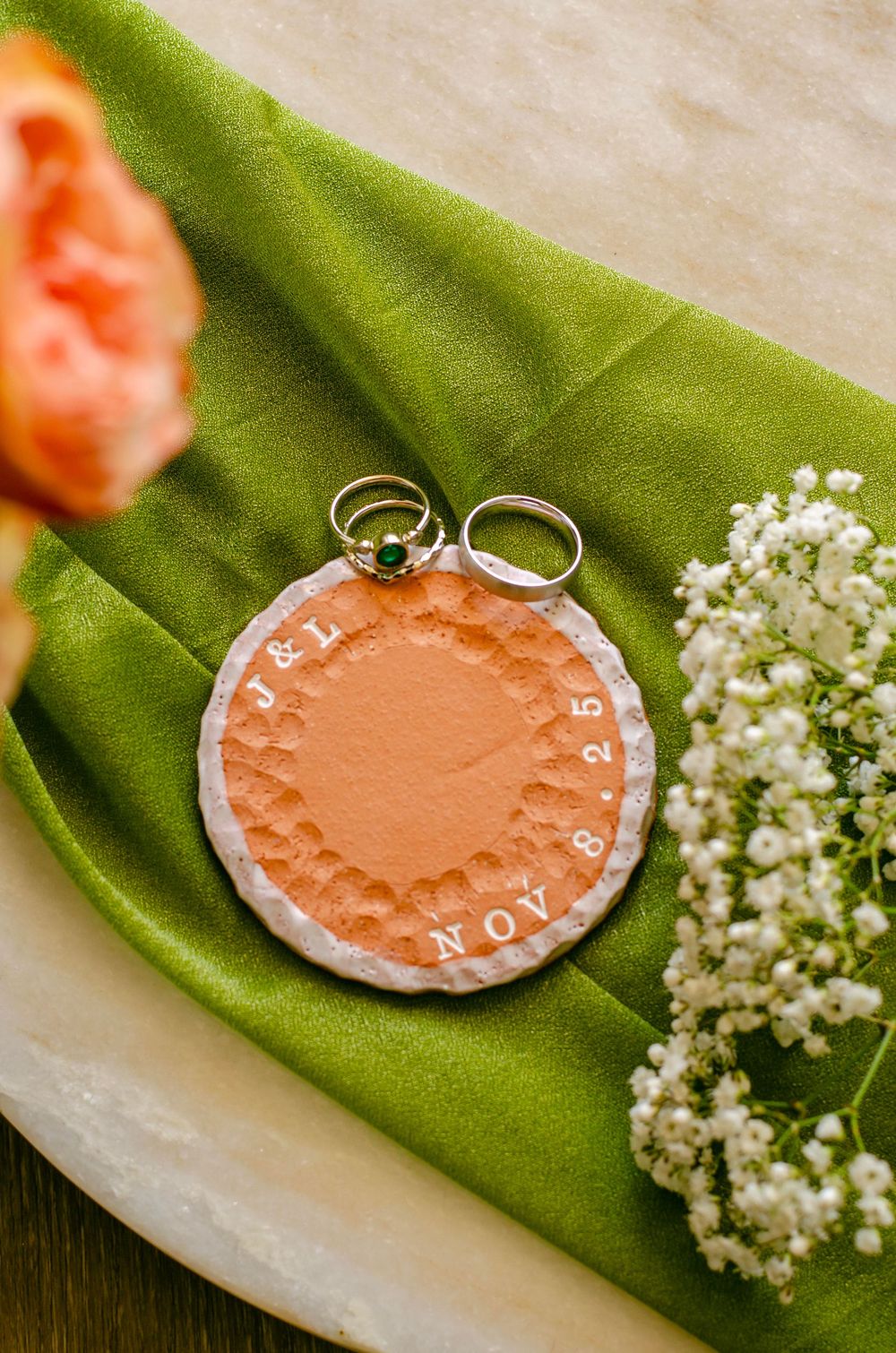 A series of pink clay wedding ring dishes displayed with delicate white baby's breath flowers on a green fabric background.