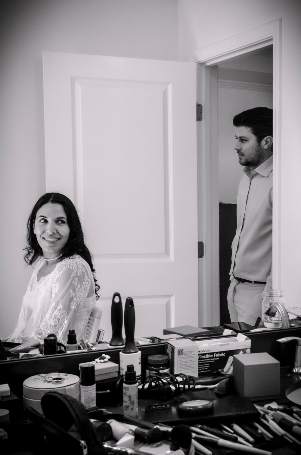 A series of black and white photos showing a person sitting at a table with makeup products and beauty supplies.