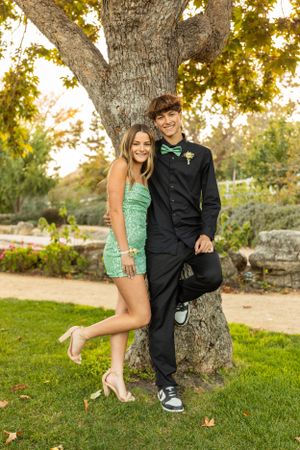 Formal couple poses by large tree trunk during sunset photo session.