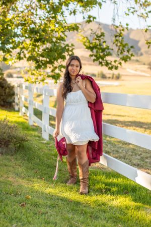 A casual portrait along a white picket fence with mountains in the background on a sunny afternoon.