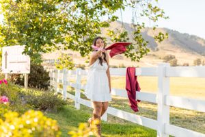 A joyful moment captured by a white fence with a burgundy shawl against rolling hills.