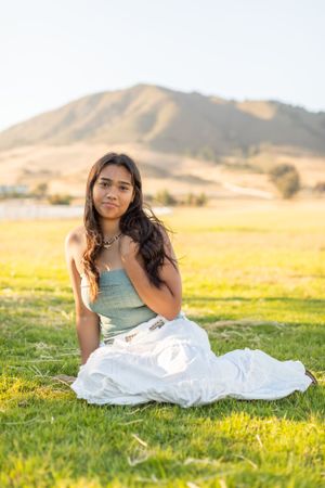 A pastoral portrait session in a grass field with mountains and golden sunlight.