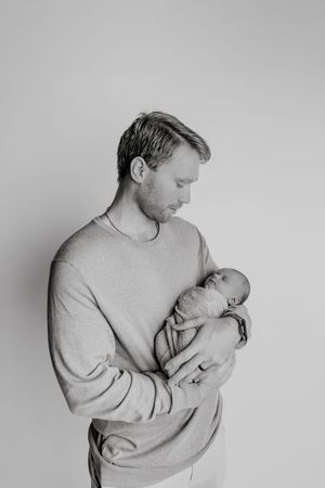 Black and white photo series showing tender moments between a parent holding and cradling a newborn baby.