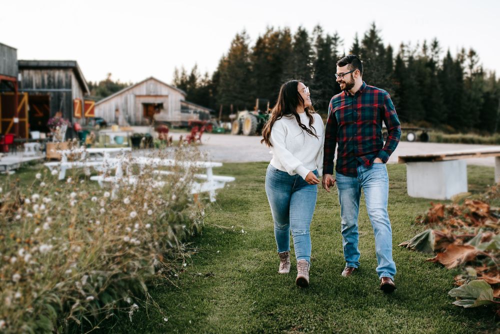 Family walking together on grassy path during golden hour with rustic buildings in background.