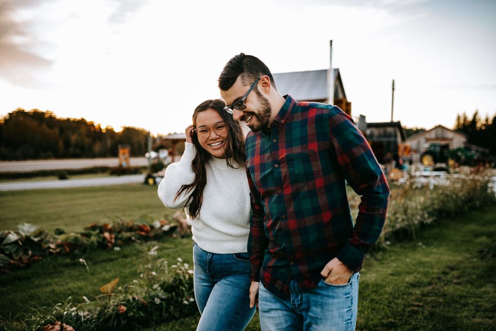 Couple in casual attire enjoying outdoor photoshoot during golden hour.