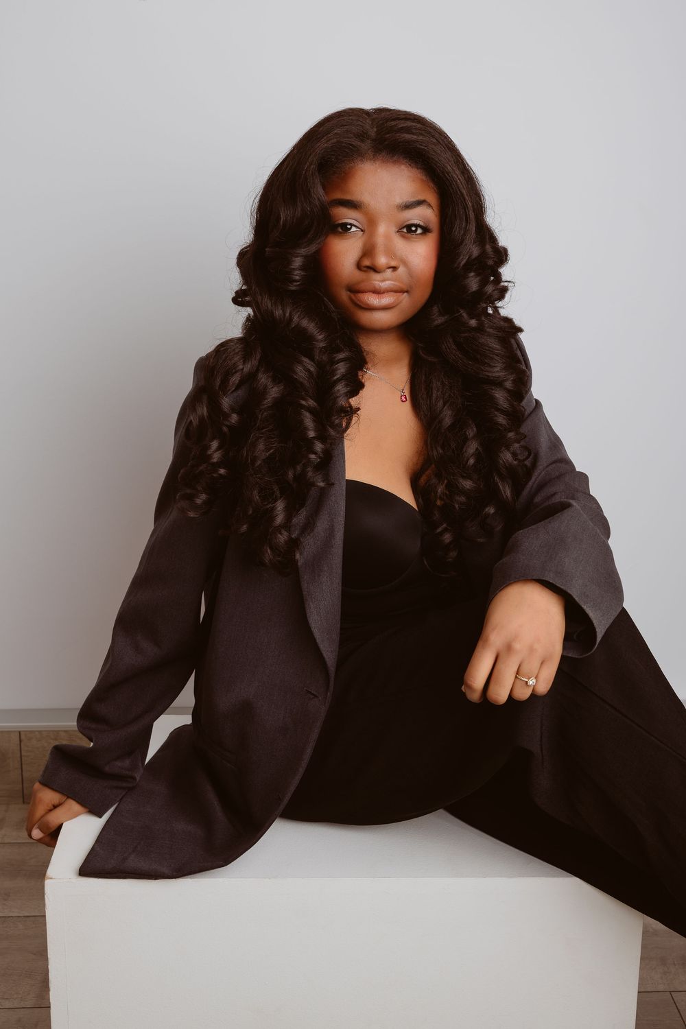 Professional portrait series showing a woman in a black blazer and top posing against a light gray background.