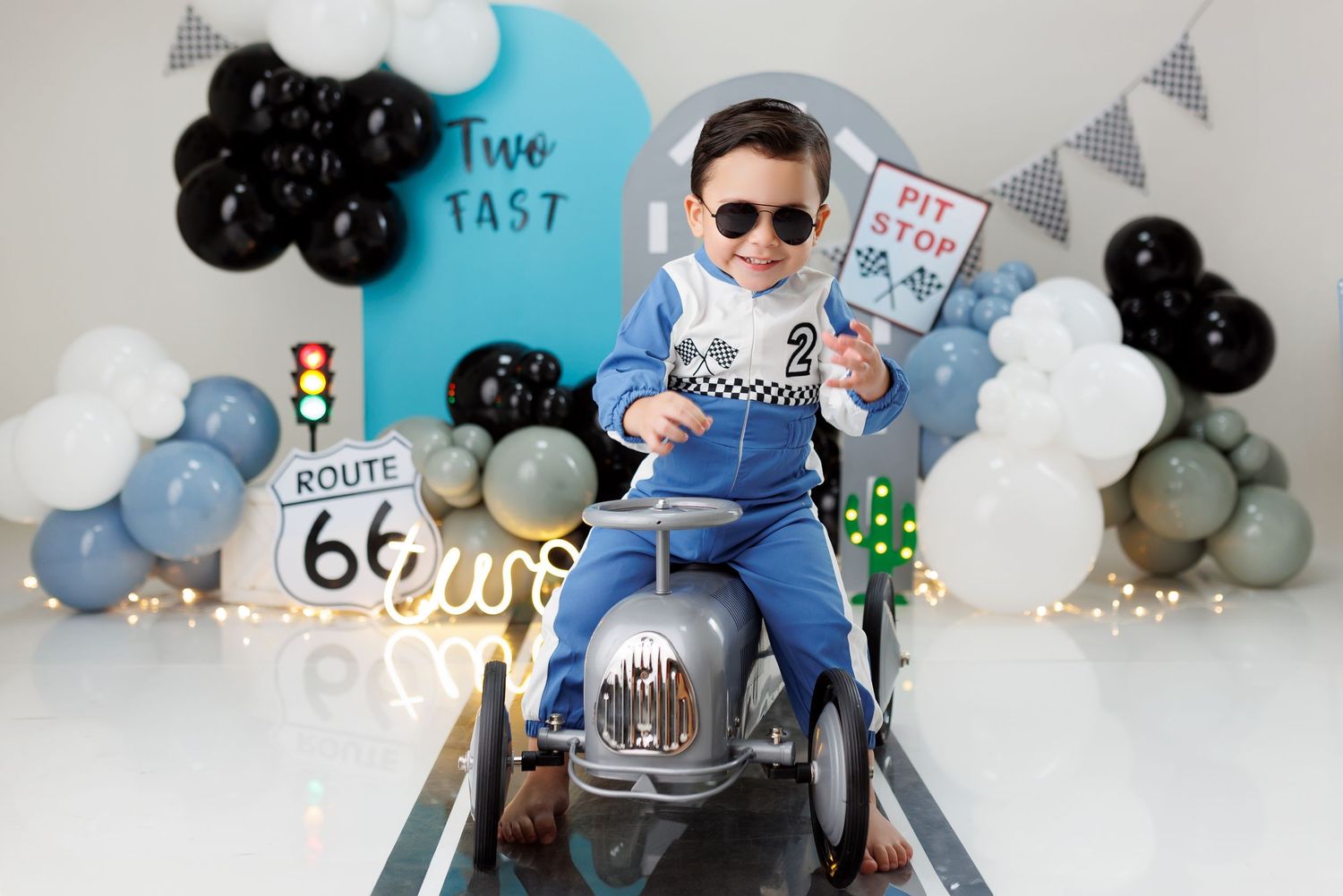 A first birthday party setup with blue and white balloons, bunting decorations, and a cake smash photo session in progress.