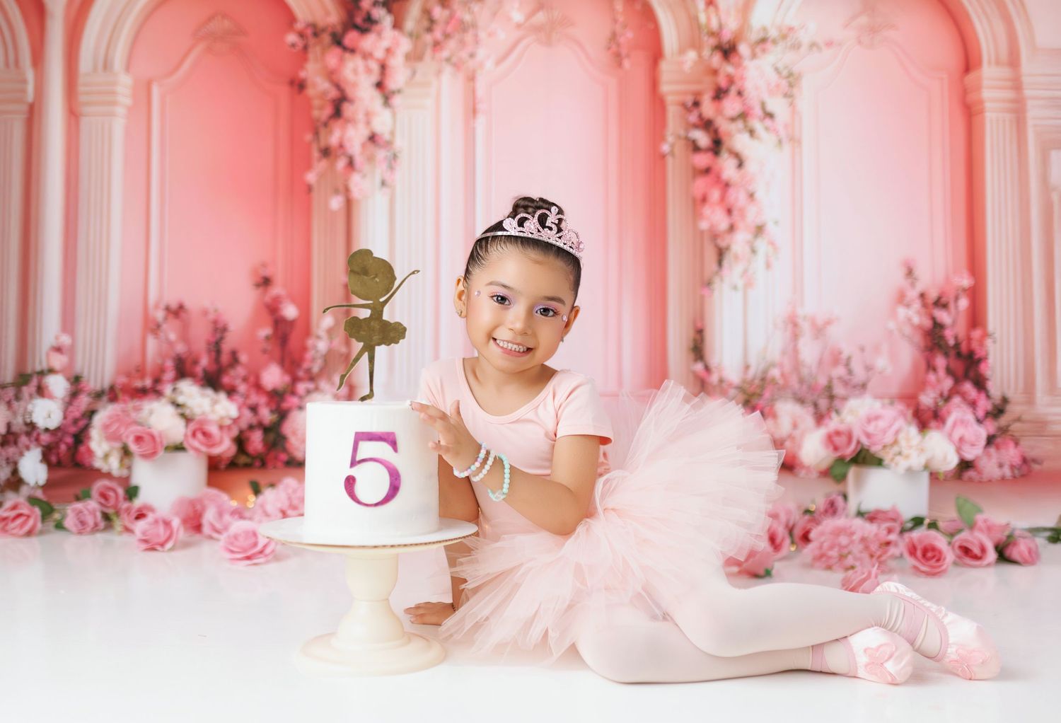 A dreamy pink and white studio setup with floral decorations and delicate lighting for a romantic photoshoot.