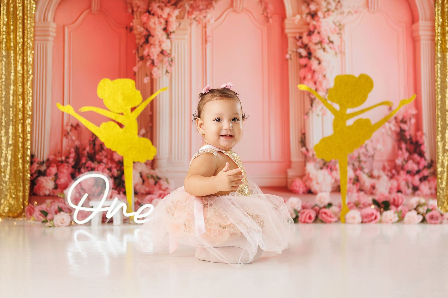 Pink and gold themed party backdrop with floral decorations and cherub silhouettes creates an elegant celebration setting.