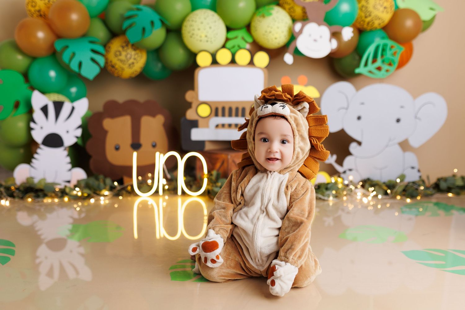 Tropical themed party decorations with green monstera leaves and gold and orange balloon garlands.