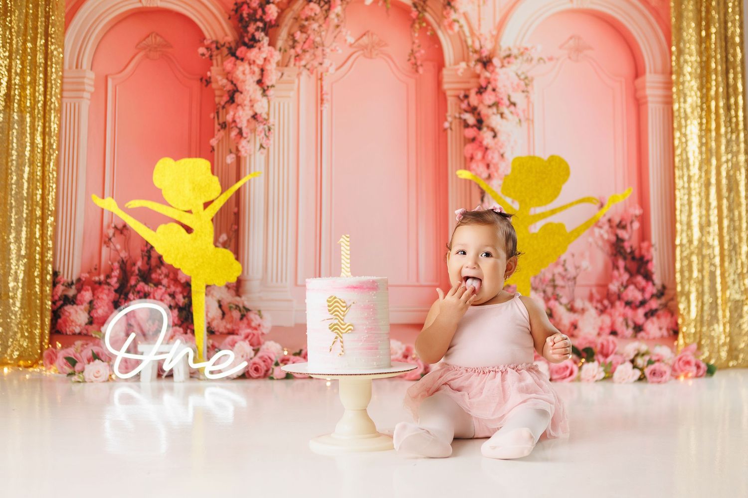 Pink and gold Valentine's Day themed party backdrop with cupid silhouettes and floral decorations.