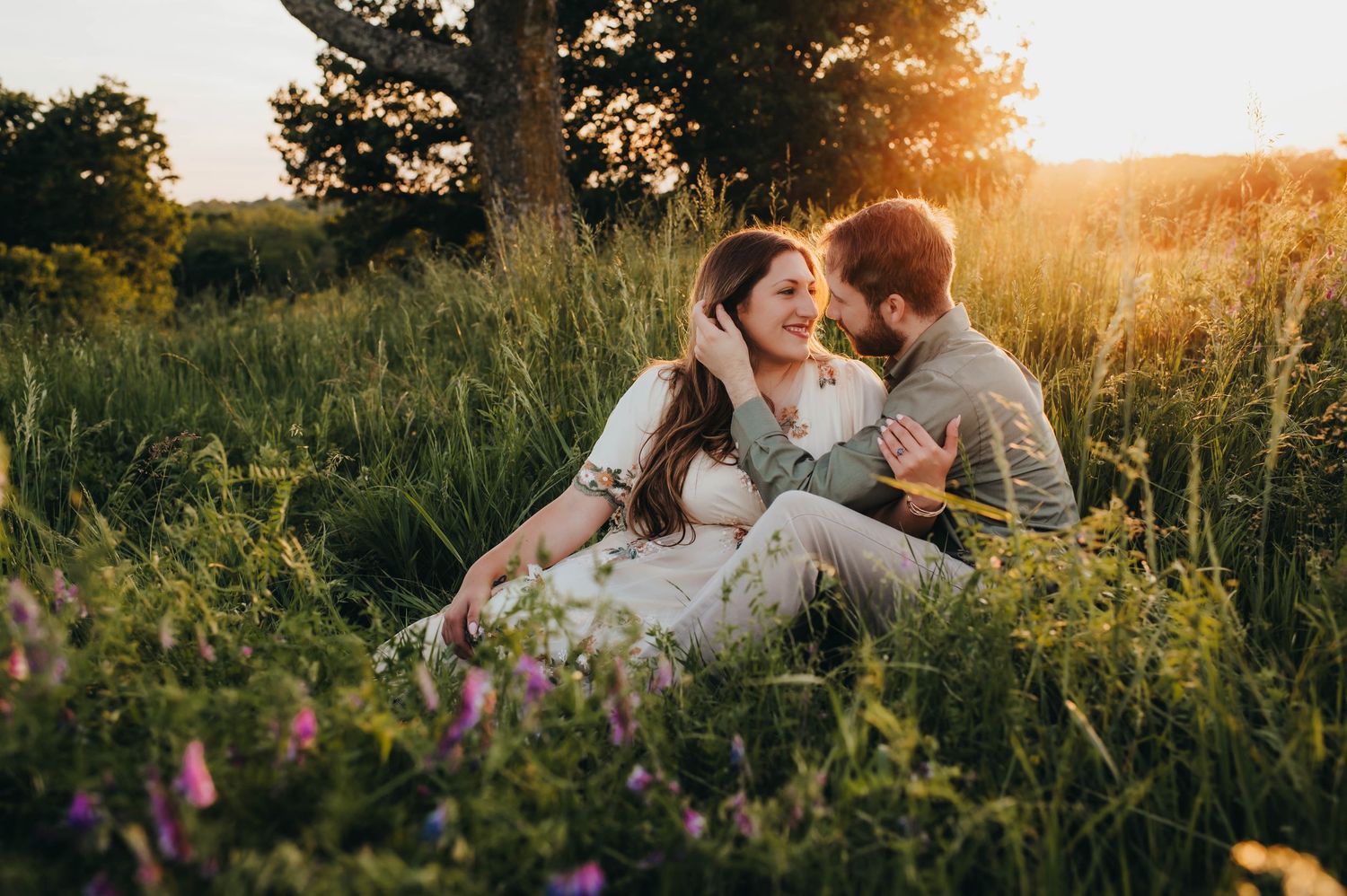 Person in a white flowing dress walks through golden sunlit fields at sunset.