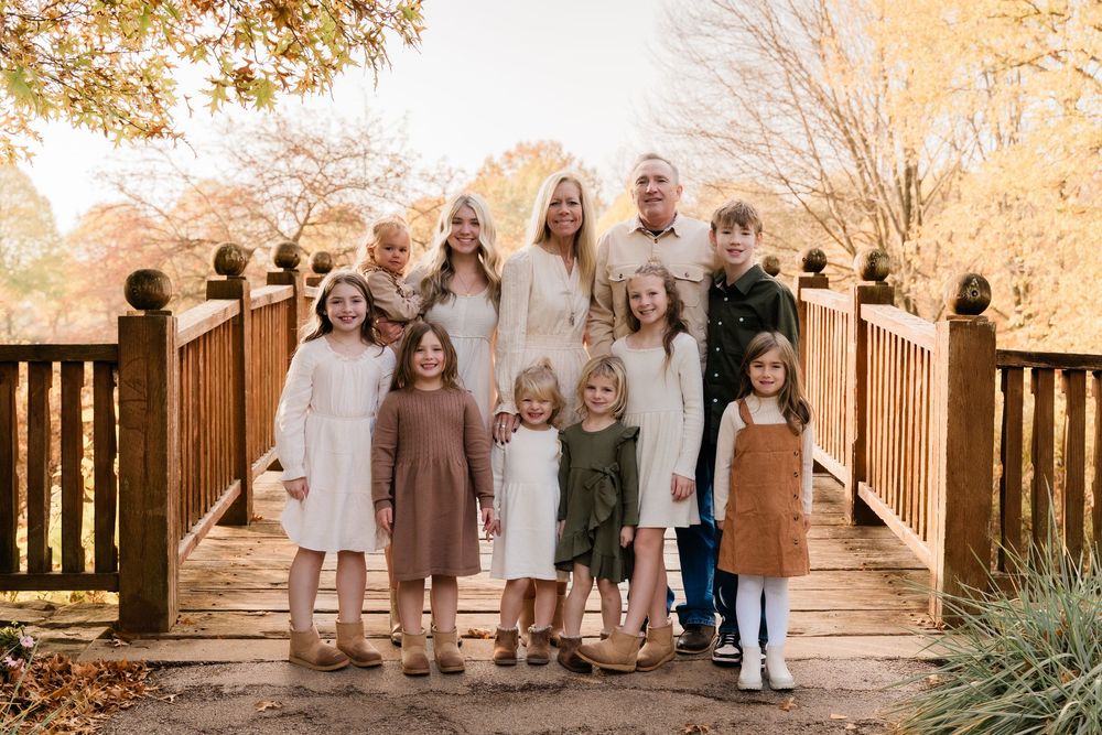 A group of people wearing coordinated beige and brown outfits pose together outdoors during golden hour.