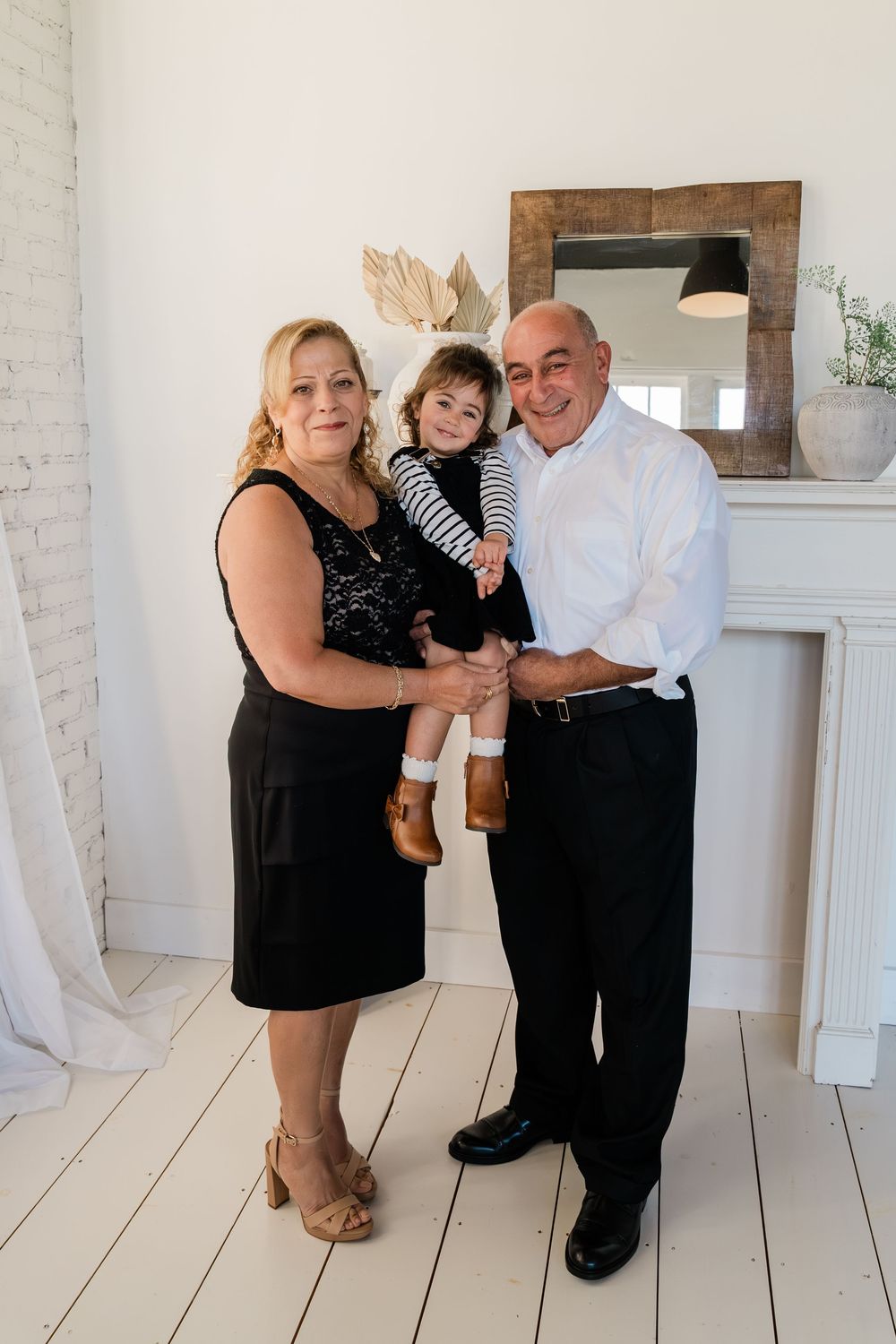 A family shares tender moments in a bright white studio space with black and white coordinated outfits.
