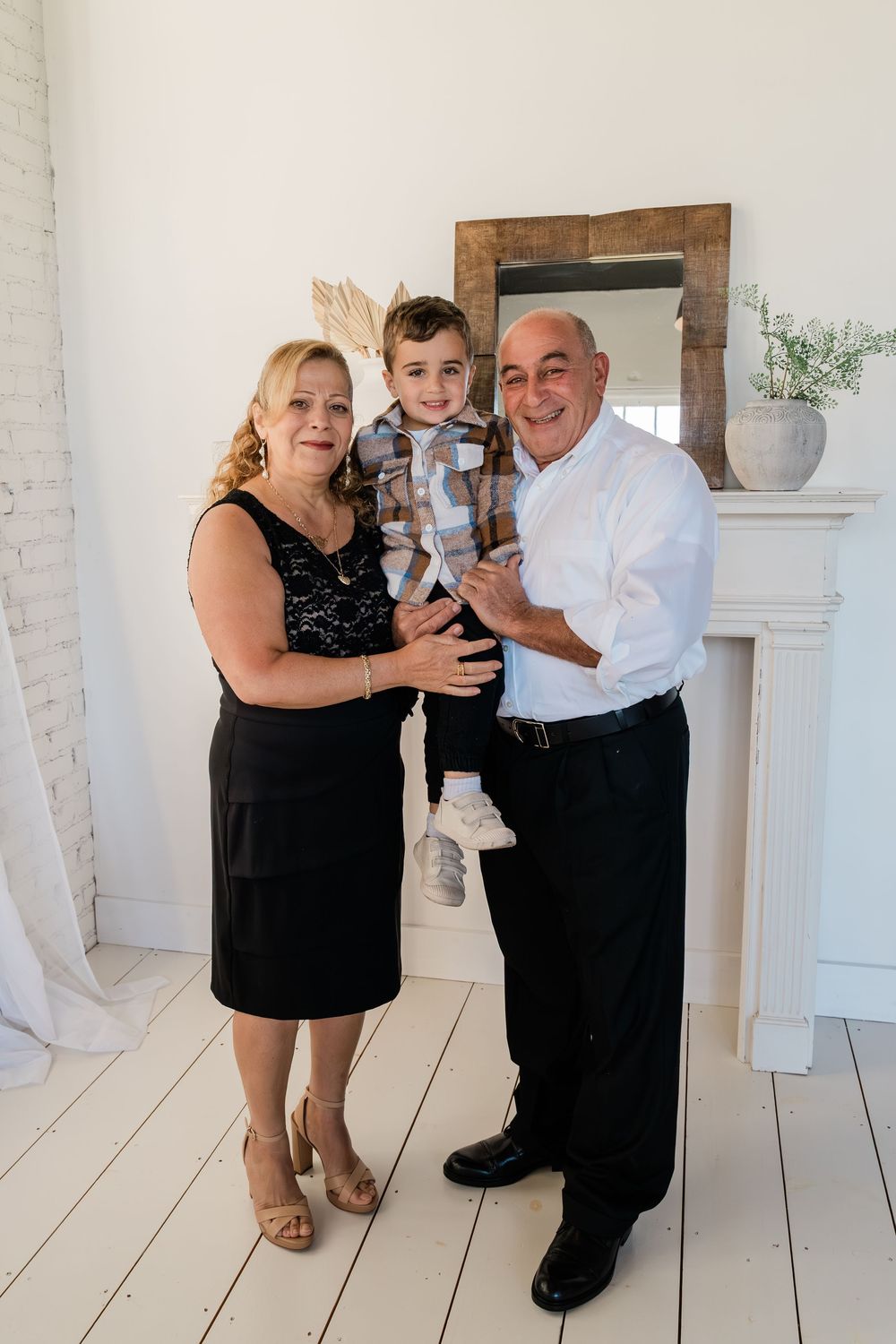 A formal family photo taken in a bright white room with rustic decor and wooden accents.