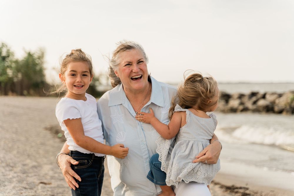 A loving family embraces and laughs together while enjoying a sunny day at the beach.