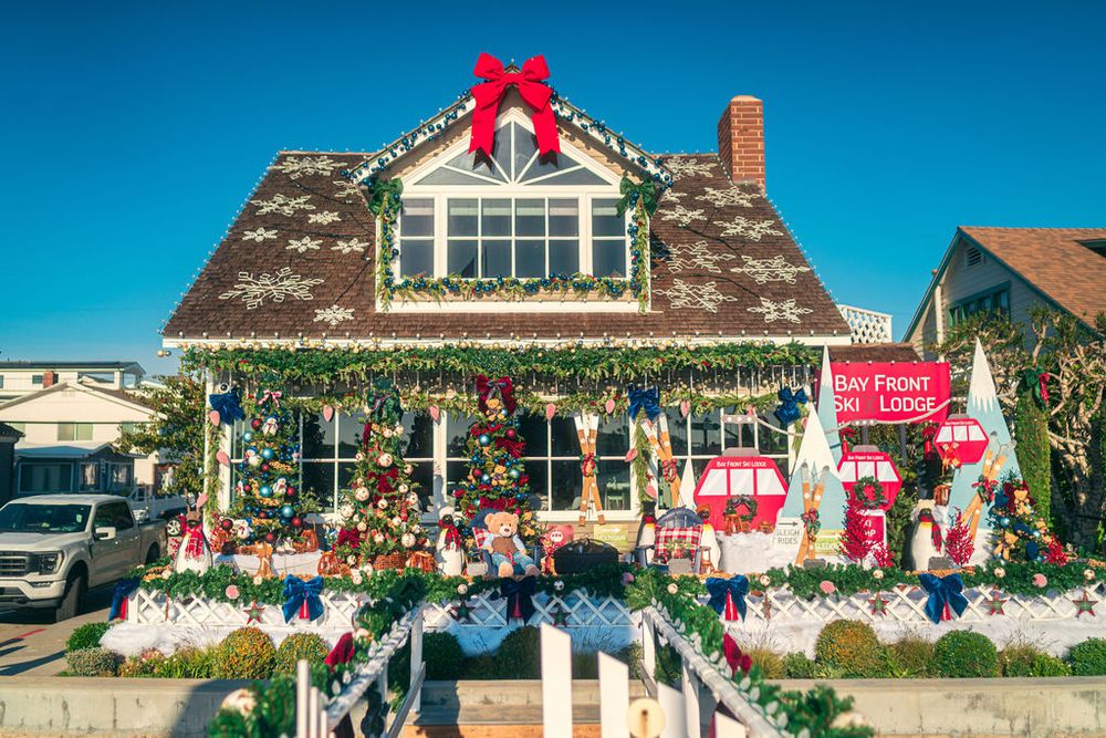 A series of houses decorated with festive red bows, garlands, and Christmas decorations along a residential street.